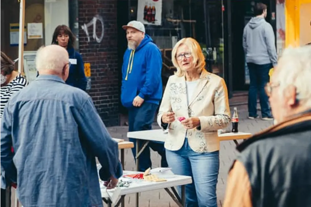 Infostand in Fußgängerzone mit Betreuenden und Besuchenden
