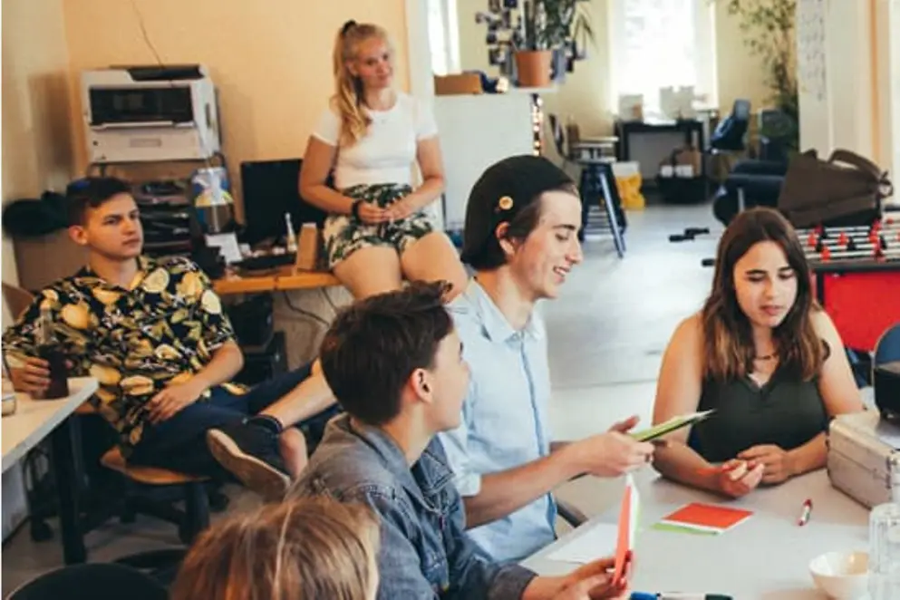 Mehrere Jugendliche sitzen um einen Tisch herum