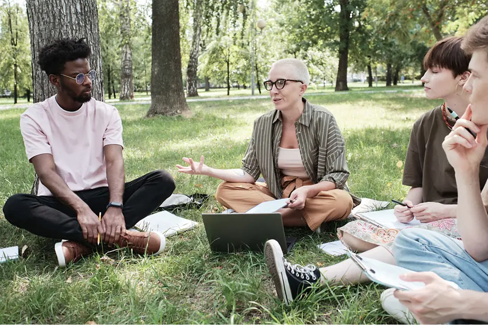 Eine Gruppe von Menschen sitzt im Park auf einer Wiese
