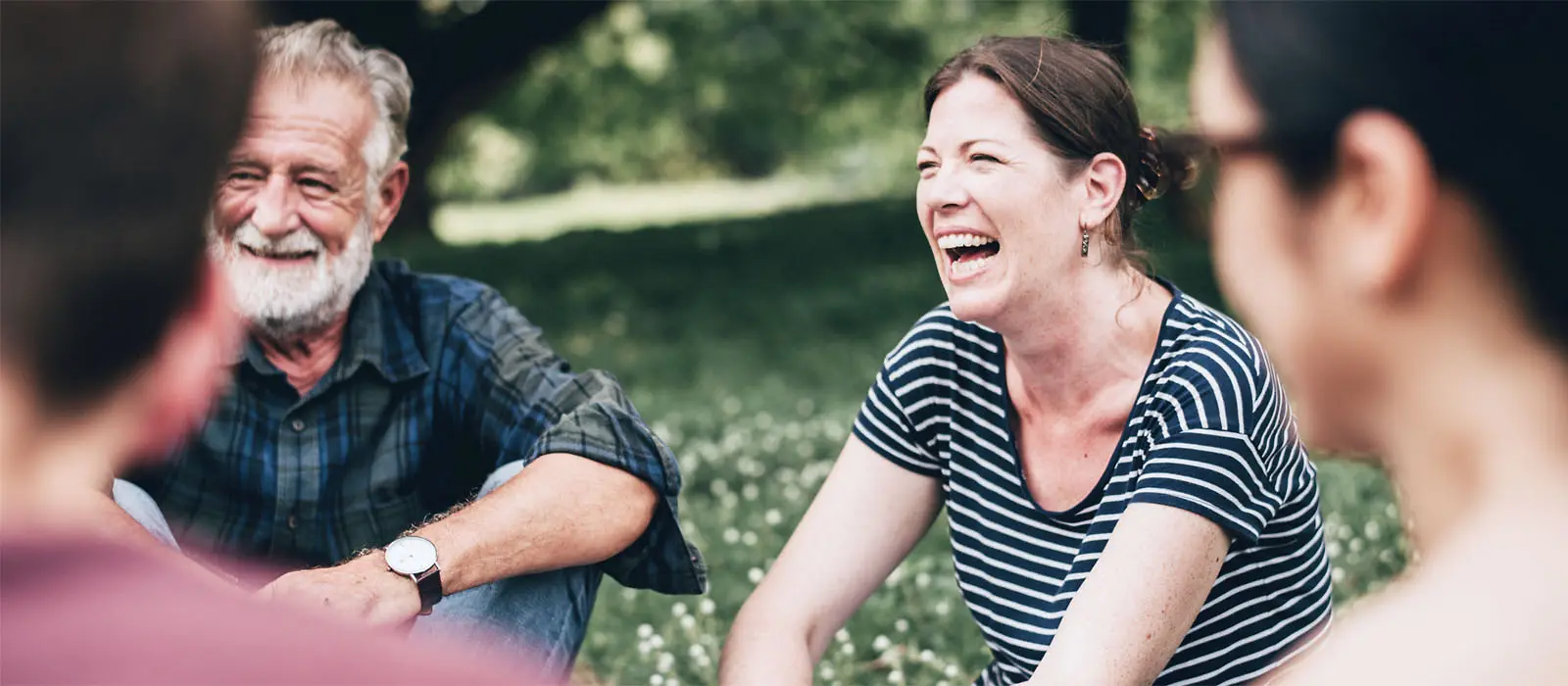 Einige lachende Menschn sitzen in einem Park