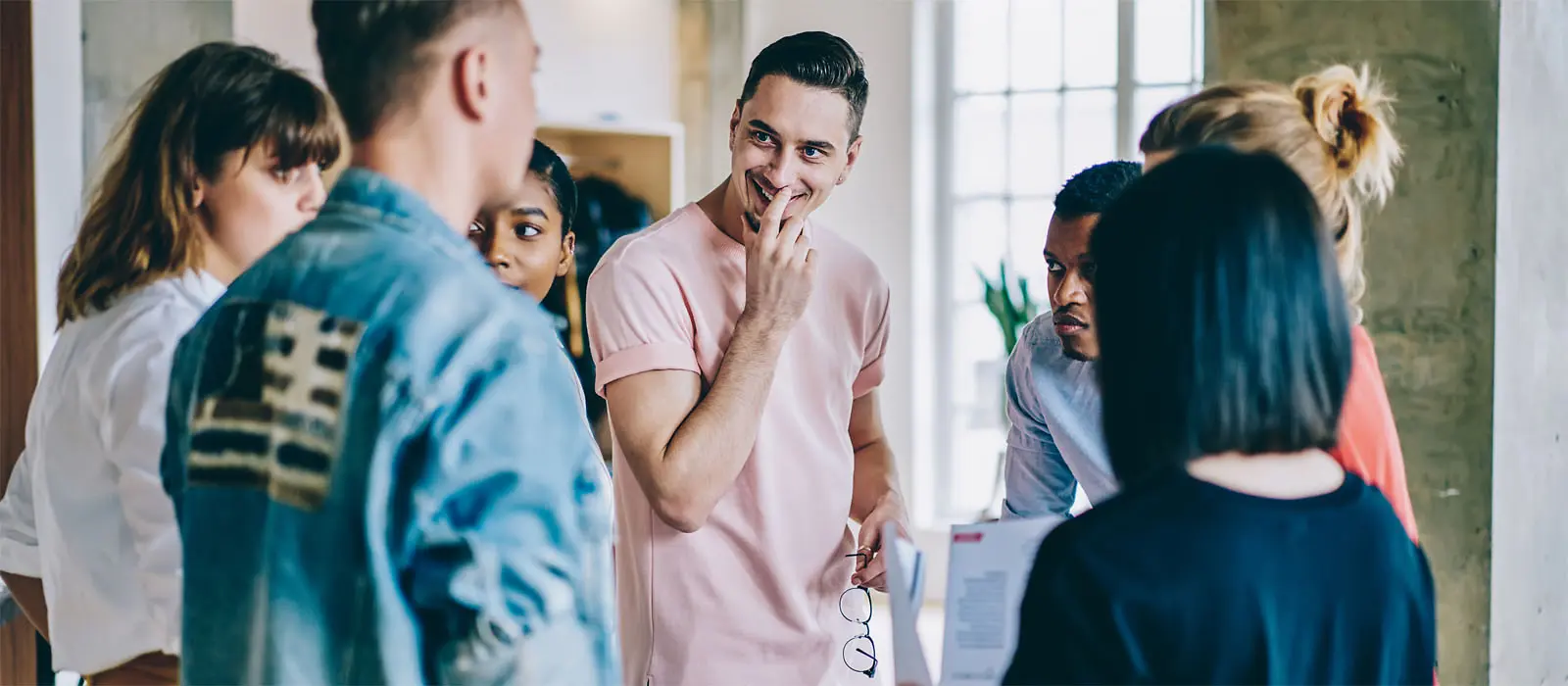 Eine Gruppe junger Menschen steht im Kreis in einem Raum