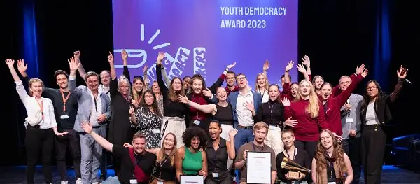 Viele junge Menschen jubeln auf der Bühne des Wettbewerbs des Jugenddemokratiepreises 2023.