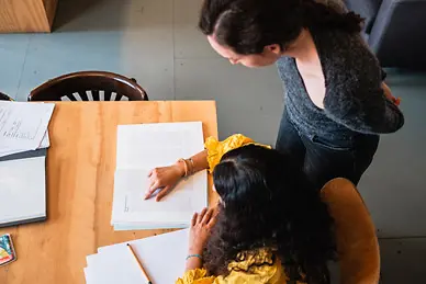 Eine Frau schaut einer anderen Frau über die Schulter.