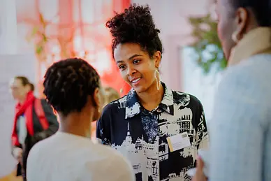 Eine Schwarze Frau sprcht mit einer zweiten Schwarzen Frau.