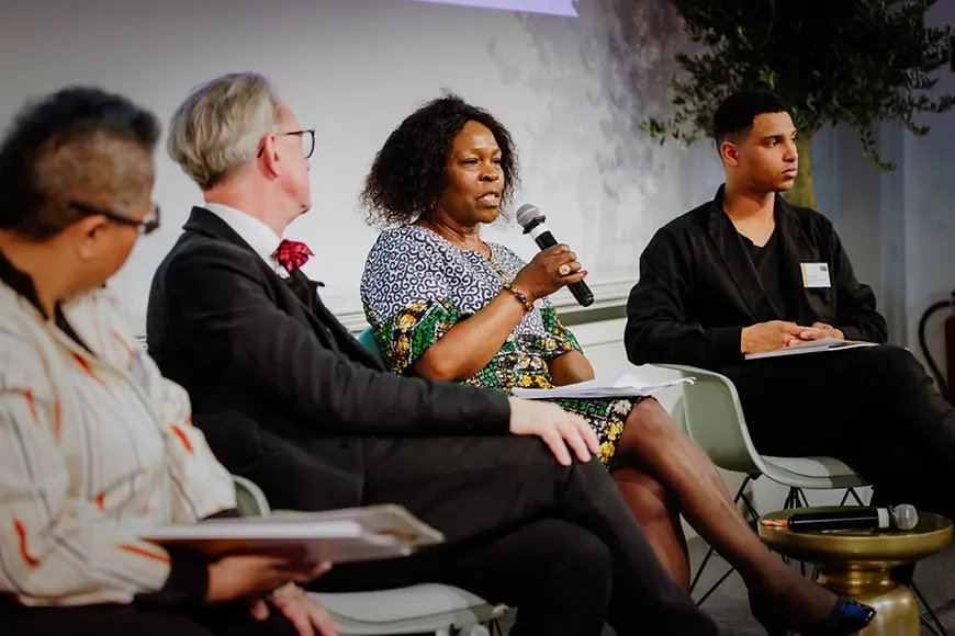 Vier Personen sitzen auf einer Bühne.