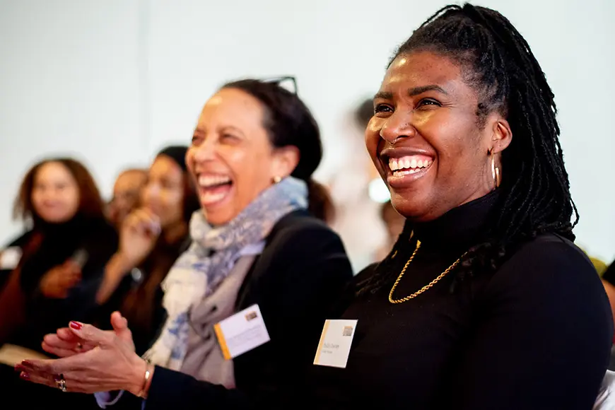 Personen sitzen im Zuschauerraum und lachen.