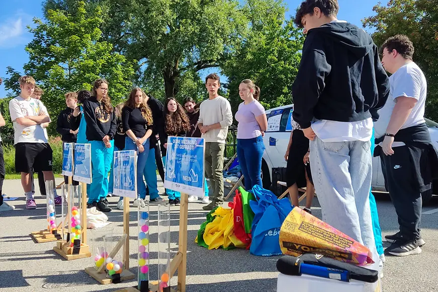 Jugendliche stehen um Säulen mit farbigen Bällen.