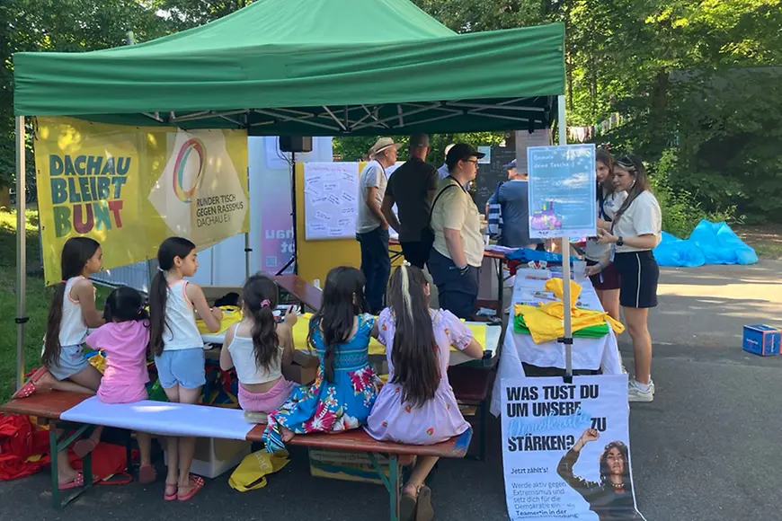 Kinder sitzen an einem Festivalstand und malen.