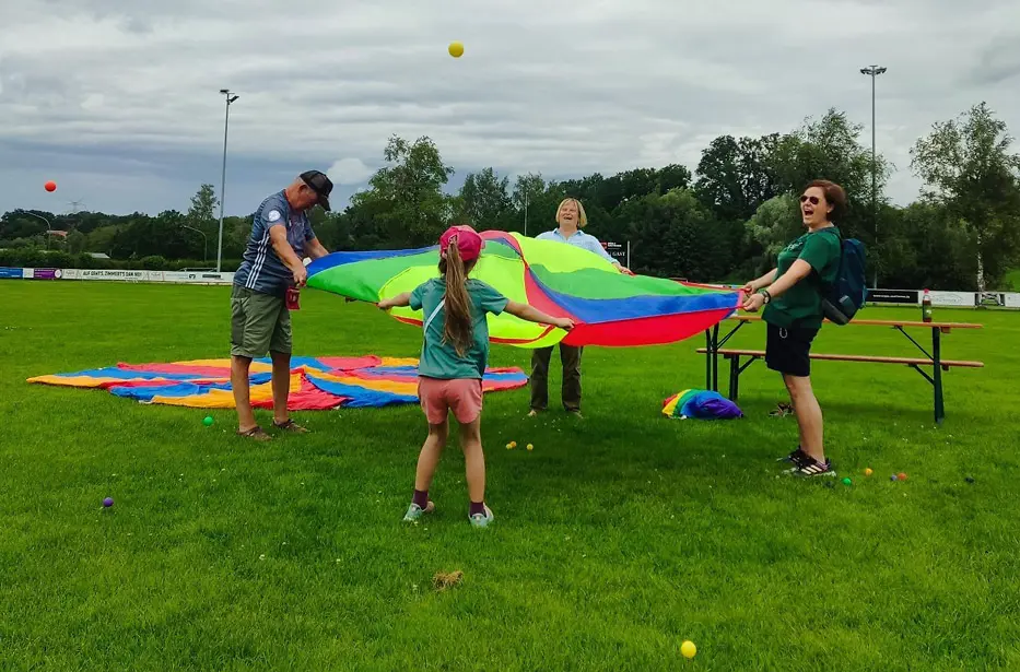 Vier Personen sind auf einem Sportplatz und halten ein Zirkustuch.