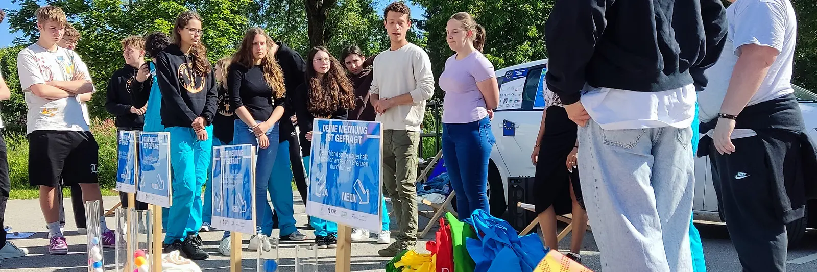 Jugendliche stehen um Säulen mit farbigen Bällen.