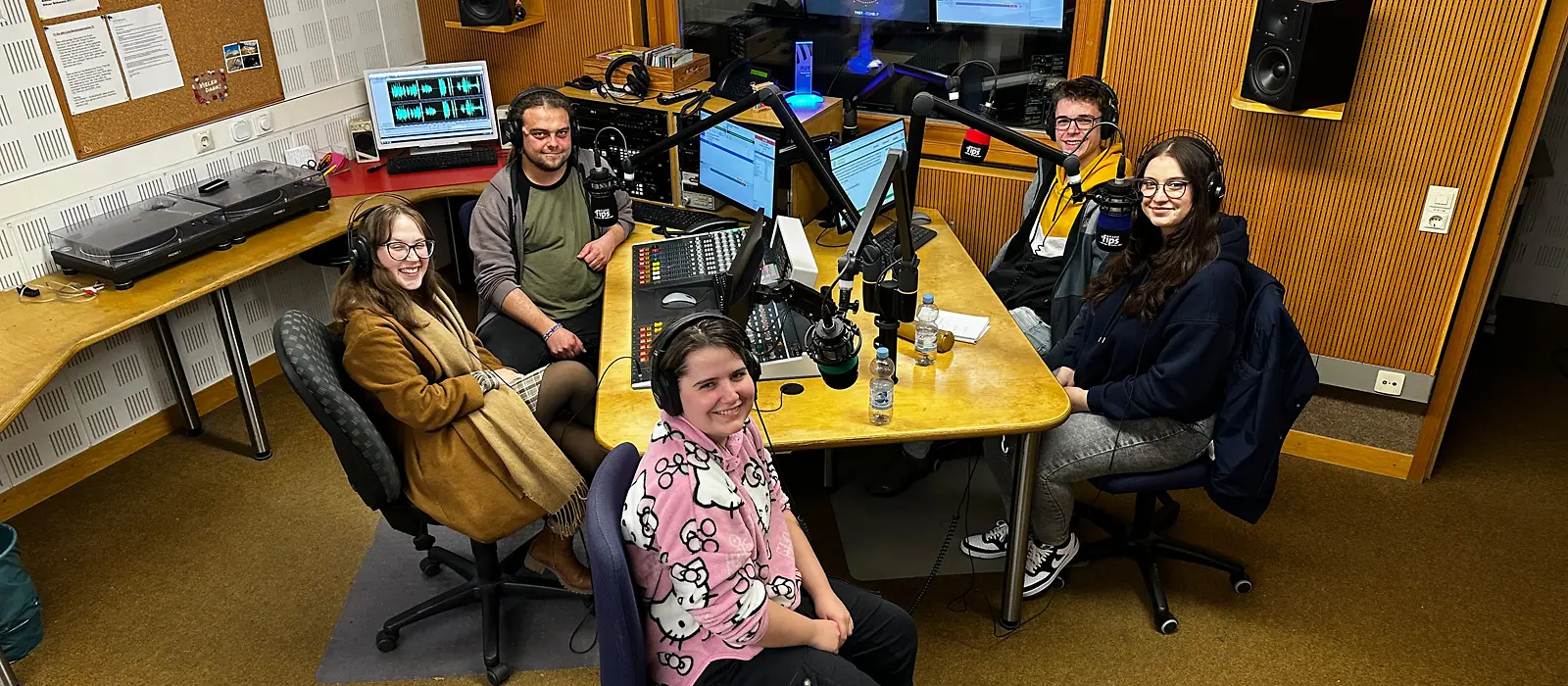 Fünf Personen sitzen in einem Aufnahmestudio.