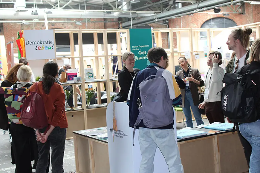 Personen stehen am Stand von "Demokratie leben!".